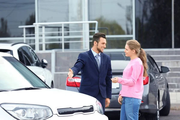Salesman showing new car to customer outdoors — Stock Photo, Image