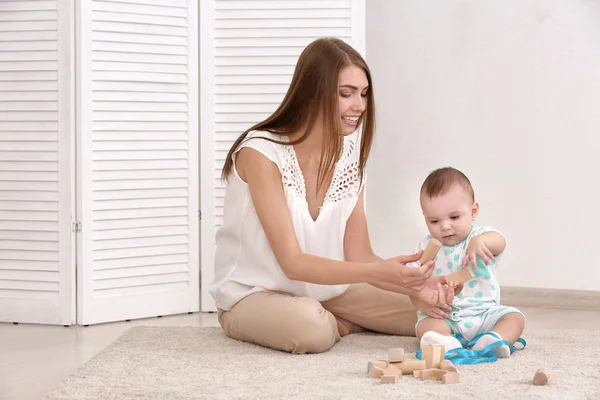 Joven madre y lindo bebé jugando en el suelo en casa —  Fotos de Stock