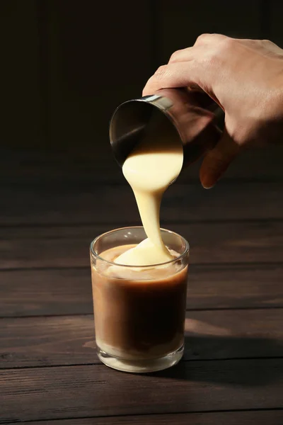 Woman adding condensed milk to coffee at table — Stock Photo, Image