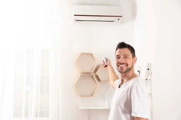 Hombre guapo encendiendo el aire acondicionado en casa — Foto de Stock