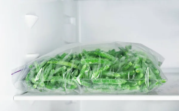 Пластиковый пакет с замороженной зеленой фасолью в холодильнике — стоковое фото