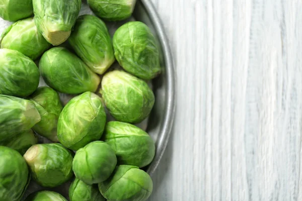 Plate with raw Brussels sprouts on wooden table, closeup — Stock Photo, Image