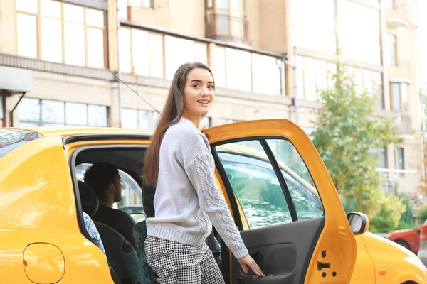 Młoda kobieta wychodzi z samochodu taxi — Zdjęcie stockowe