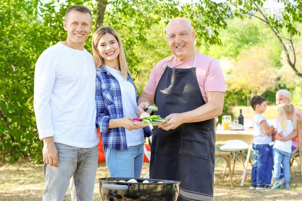 Lykkelig familie som har grillfest utendørs – stockfoto