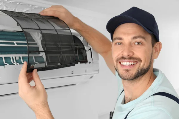 Técnico masculino limpeza ar condicionado dentro de casa — Fotografia de Stock