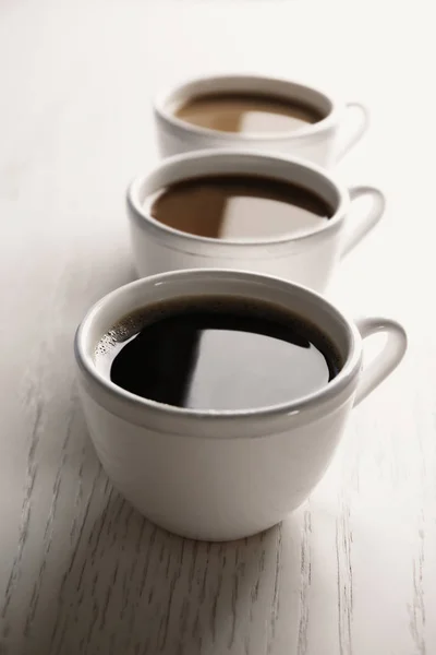 Copos com delicioso café no fundo claro — Fotografia de Stock
