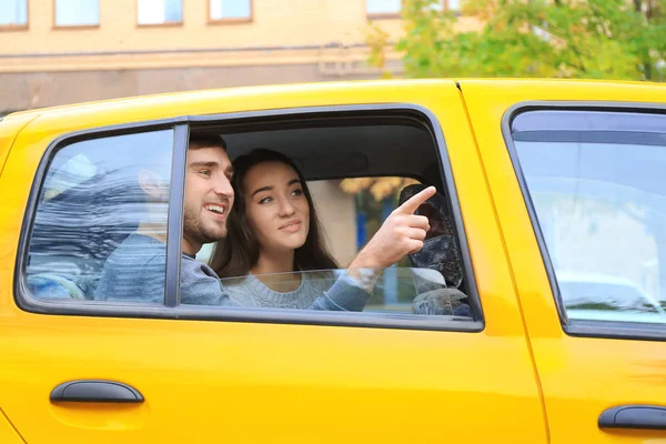 Gelukkige jonge paar op achterbank van taxi-auto — Stockfoto