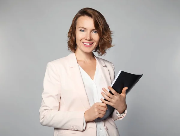 Gerente femenina con cuaderno sobre fondo gris — Foto de Stock