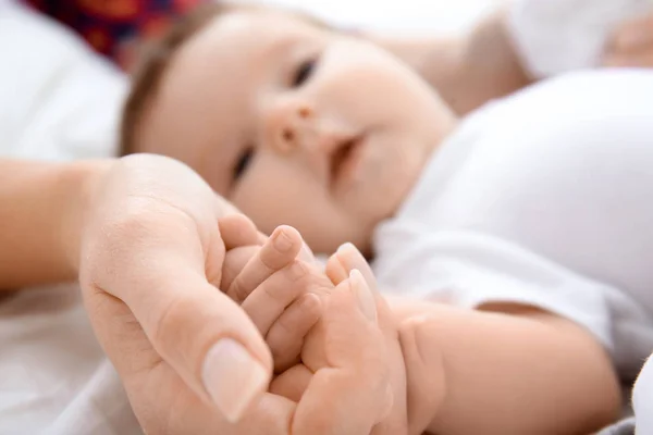 Baby holding mother's hand on bed — Stock Photo, Image