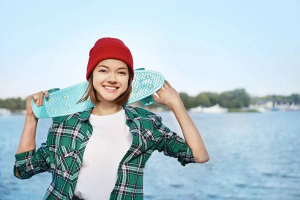 Bokovky dívka s skateboard na břehu řeky — Stock fotografie