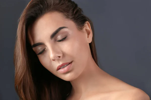 Hermosa joven con extensiones de pestañas sobre fondo gris — Foto de Stock