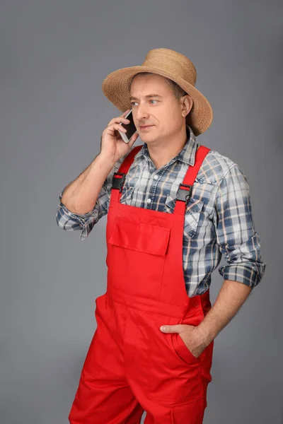 Agronom im Mantel telefoniert vor grauem Hintergrund — Stockfoto