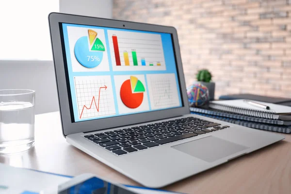 Lugar de trabajo con ordenador portátil y diagramas — Foto de Stock