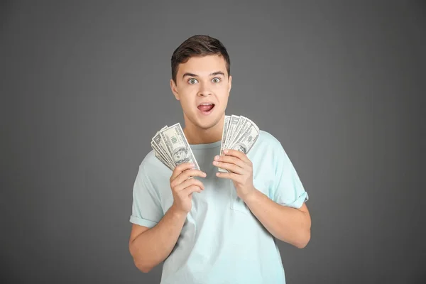 Érzelmi fiatalember dollár számlák a szürke háttér — Stock Fotó