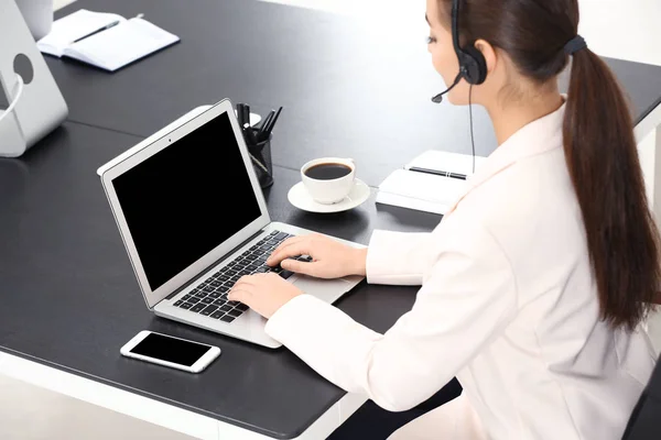 Responsabile della consulenza femminile con auricolare utilizzando laptop in ufficio — Foto Stock