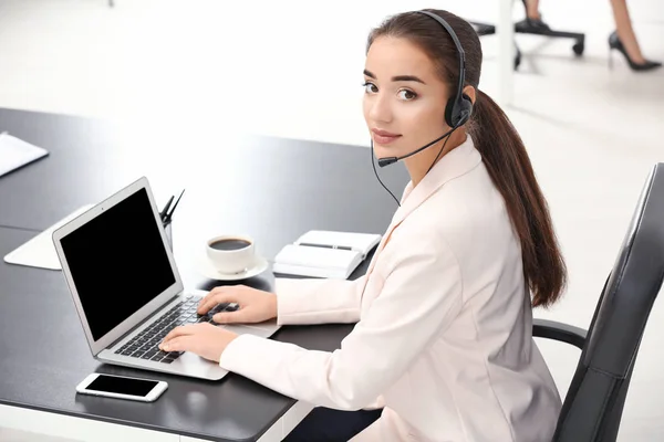 Female consulting manager with headset using laptop in office