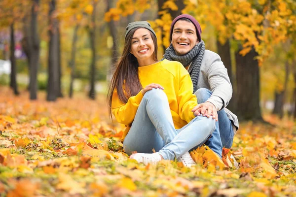 Молода пара сидить на землі в осінньому парку — стокове фото