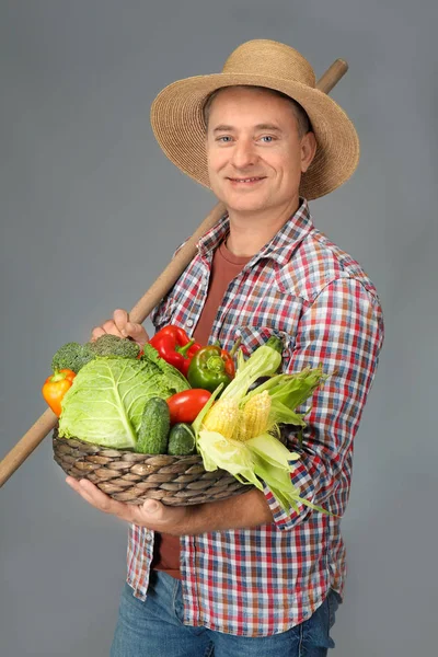 Agronom med färska grönsaker på grå bakgrund — Stockfoto