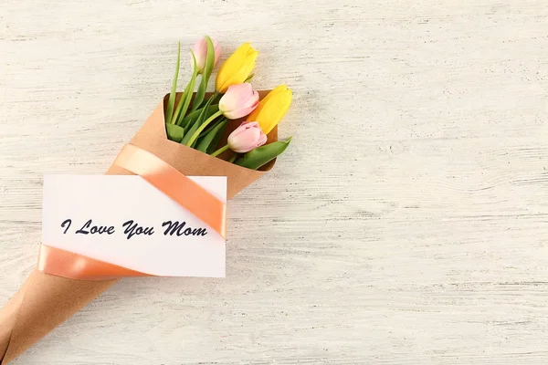 Ramo de flores con tarjeta para el día de la madre sobre fondo de madera —  Fotos de Stock