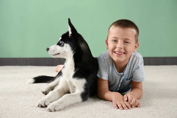 Mignon chiot husky et petit garçon sur le sol à la maison — Photo