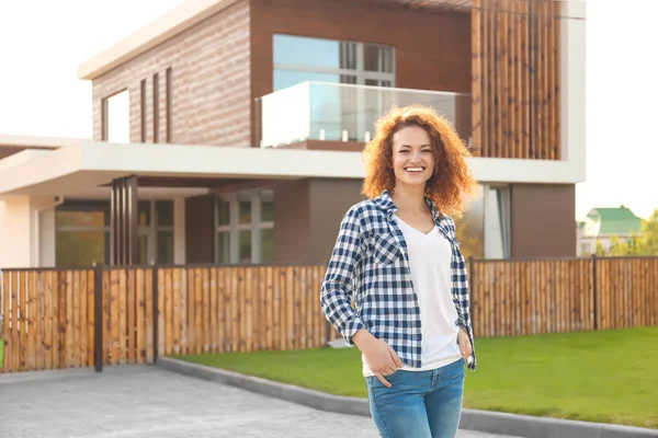 Happy young woman near house