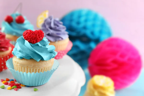 Stand with tasty bright cupcakes on blurred background, closeup — Stock Photo, Image