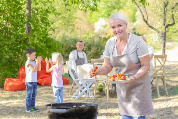 Mujer madura cocinando verduras en la parrilla barbacoa al aire libre —  Fotos de Stock