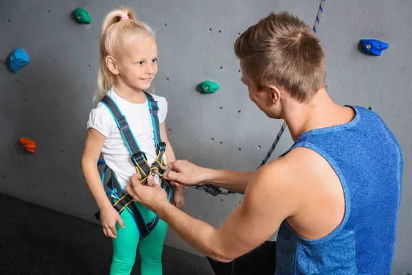 Instructor poniendo arnés en niña en gimnasio de escalada — Foto de Stock