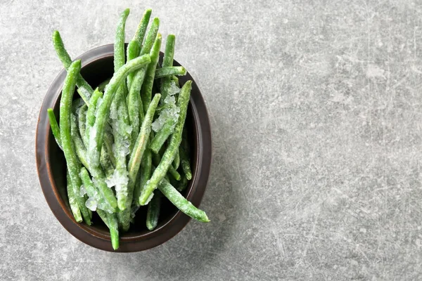 Bol avec haricots verts congelés sur fond gris — Photo