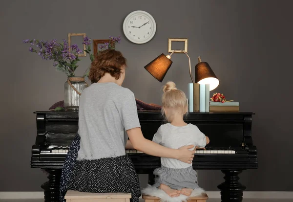 Meisje met de leraar leren piano spelen binnenshuis — Stockfoto