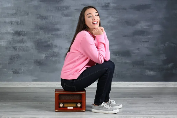 Молодая женщина, сидящая на радиоприемнике — стоковое фото