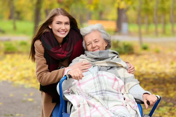 Engelli kadın kıdemli ve parkta genç caregiver — Stok fotoğraf