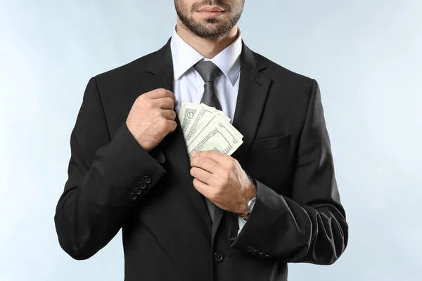 Businessman with dollar bills on light background — Stock Photo, Image