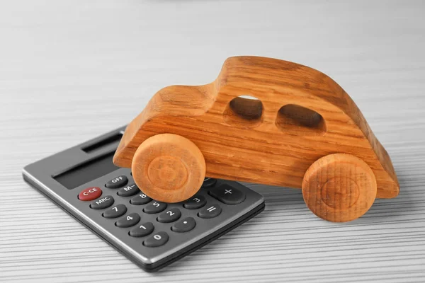 Coche de madera y calculadora en la mesa —  Fotos de Stock