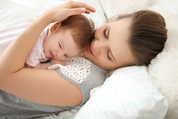 Joven madre sosteniendo lindo bebé en la cama en casa — Foto de Stock