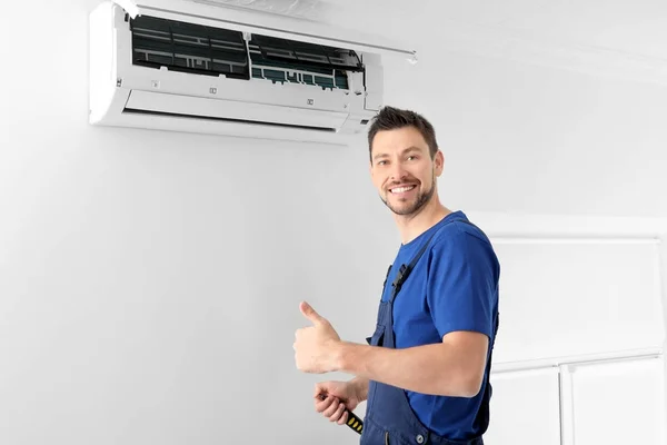 Técnico masculino após reparo bem sucedido de ar condicionado dentro de casa — Fotografia de Stock