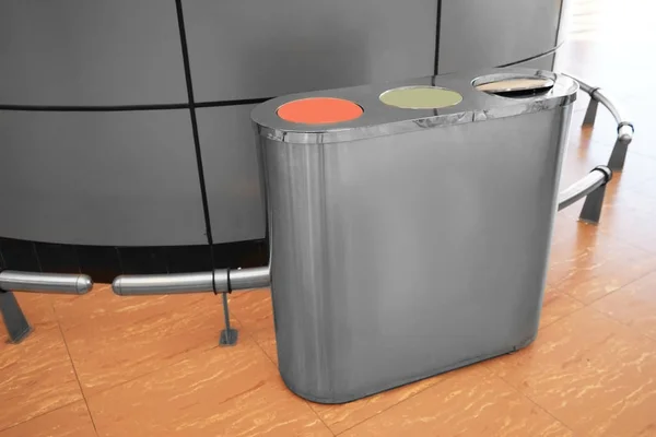 Metal bin with sections for different types of trash indoors. Recycling concept