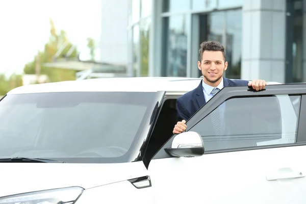Продавец стоит рядом с новым автомобилем на открытом воздухе — стоковое фото
