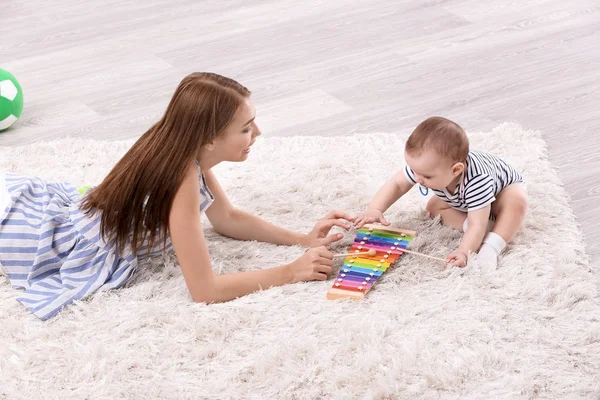 Jonge moeder en schattige baby spelen op verdieping thuis — Stockfoto