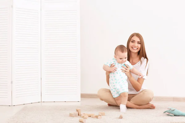 Młoda matka i słodkie dziecko bawiące się na piętrze w domu — Zdjęcie stockowe