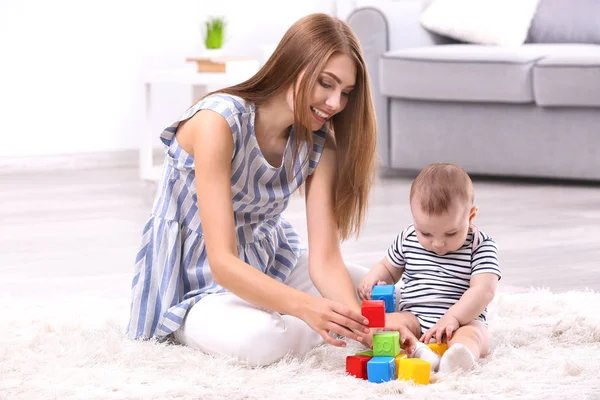 Jovem mãe e bebê bonito jogando no chão em casa — Fotografia de Stock