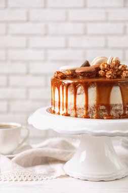Duvara karşı masada lezzetli karamelli pasta ile stand