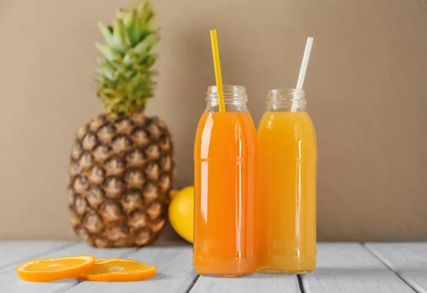 Bottles with fresh juices on table against color wall — Stock Photo, Image