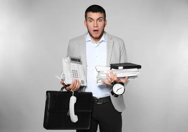 Gestor masculino emocional com material de escritório em fundo cinza — Fotografia de Stock