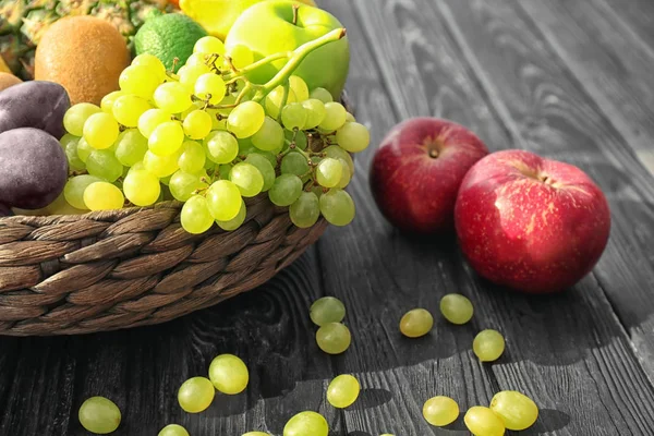 Basket and fresh fruits on wooden table — Stock Photo, Image