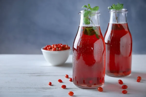 Garrafas com suco de goji saudável na mesa de madeira — Fotografia de Stock