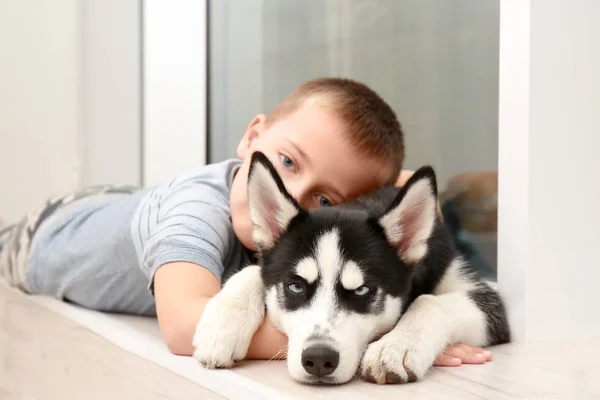 Chiot husky mignon et petit garçon à la maison — Photo