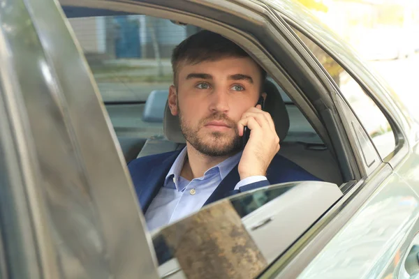 Молодой бизнесмен разговаривает по телефону на заднем сидении такси — стоковое фото