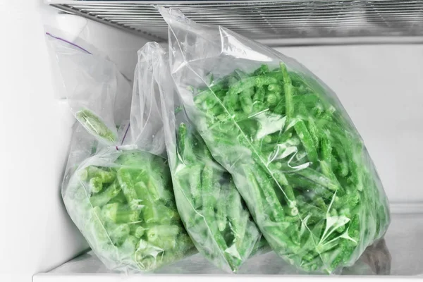 Plastic bags with frozen green beans in refrigerator — Stock Photo, Image