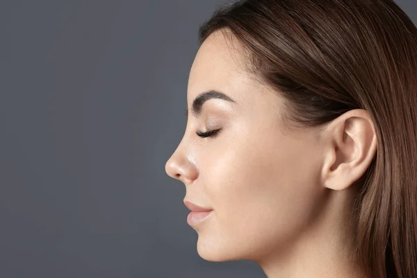 Beautiful young woman with eyelash extensions on grey background — Stock Photo, Image